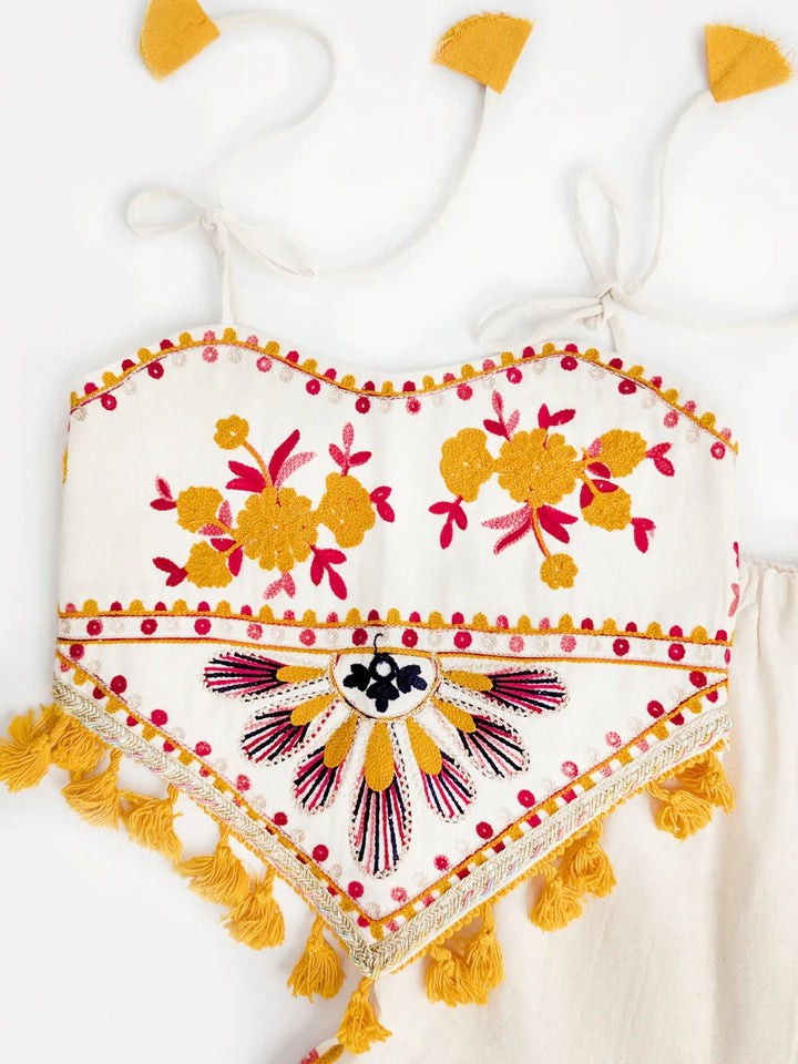 Heart-shaped embroidered pillow with floral patterns and tassels on a white background