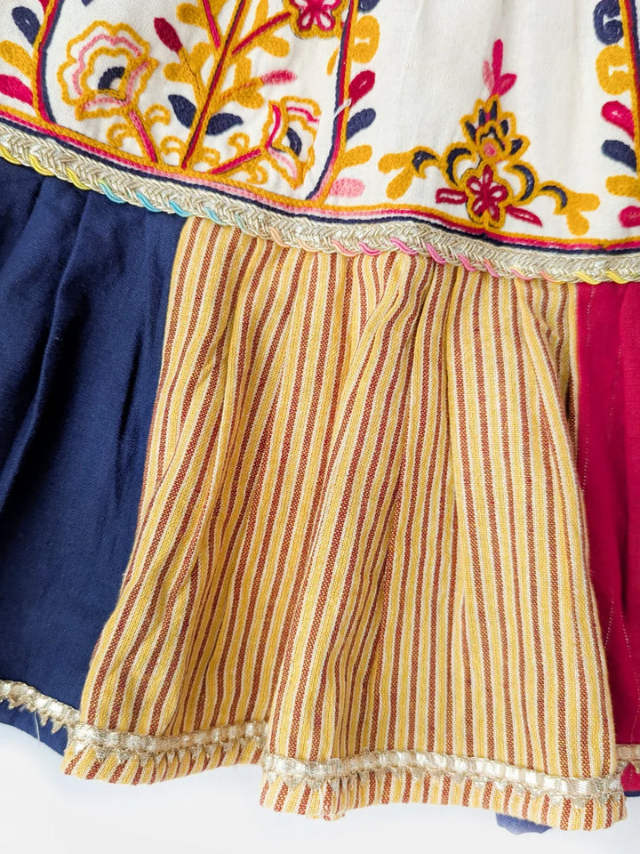 Colorful traditional outfit with embroidered top and striped shorts on a white background