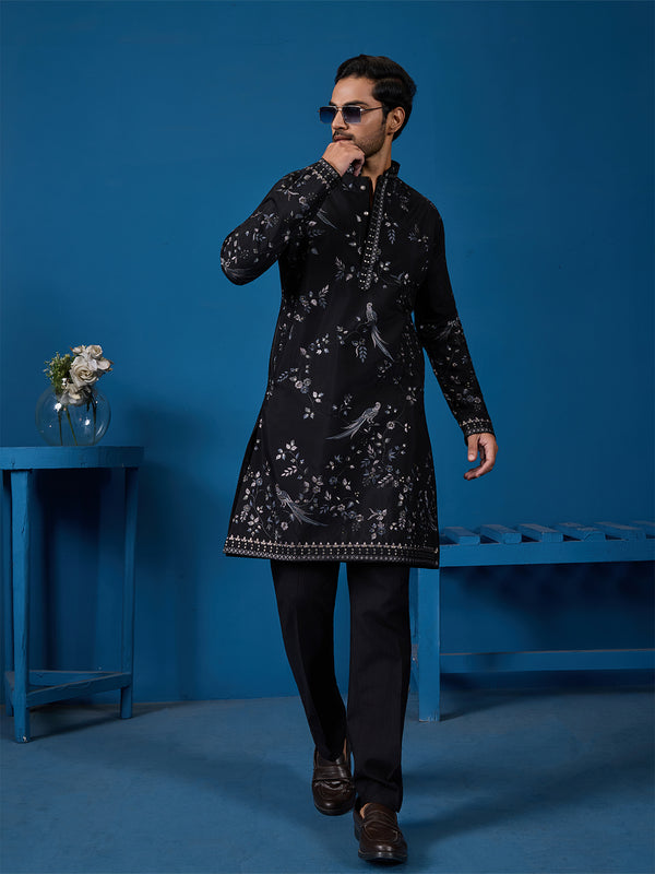 Man wearing a black embroidered sherwani against a blue background