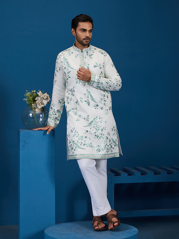 Man wearing a white floral kurta with white pants against a blue background