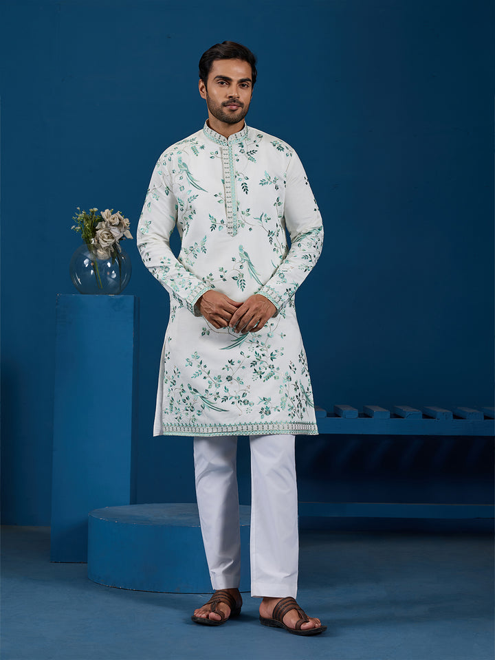 Man wearing a white kurta with green floral patterns against a blue background
