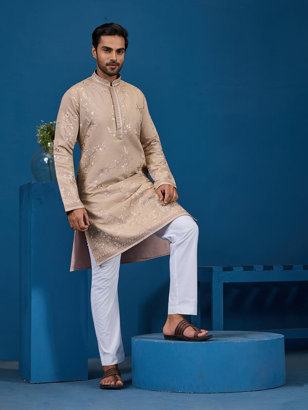 Man wearing a beige kurta with white pants on a blue background