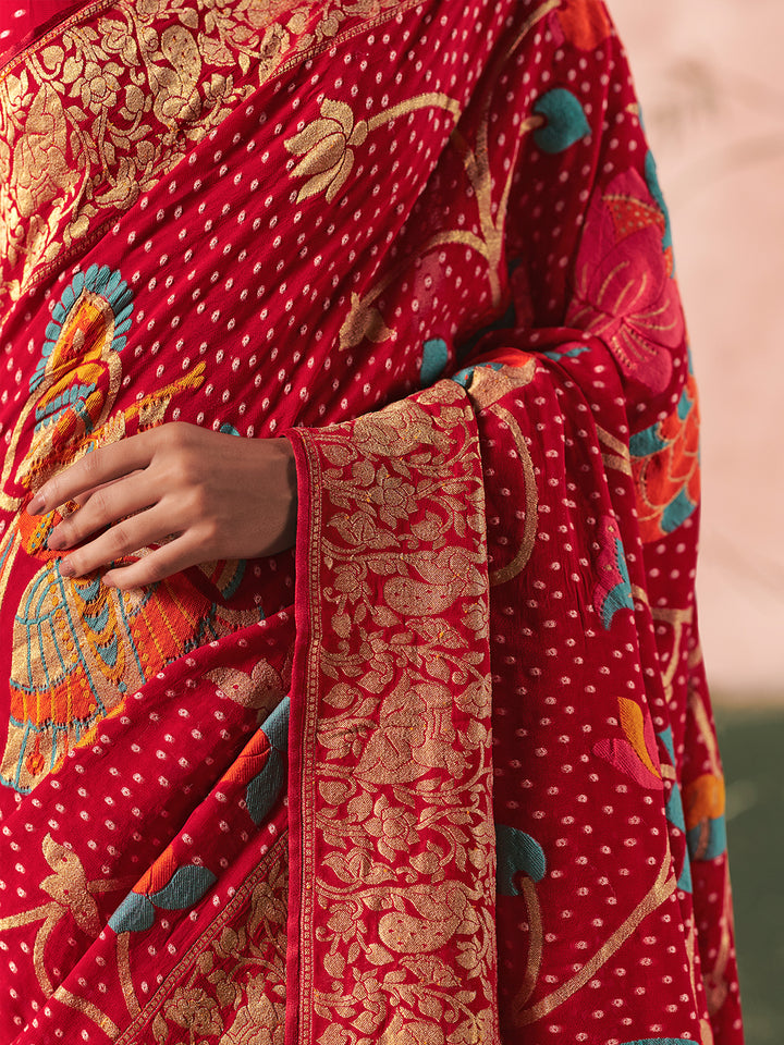 Red saree with intricate gold and multicolor patterns on a neutral background