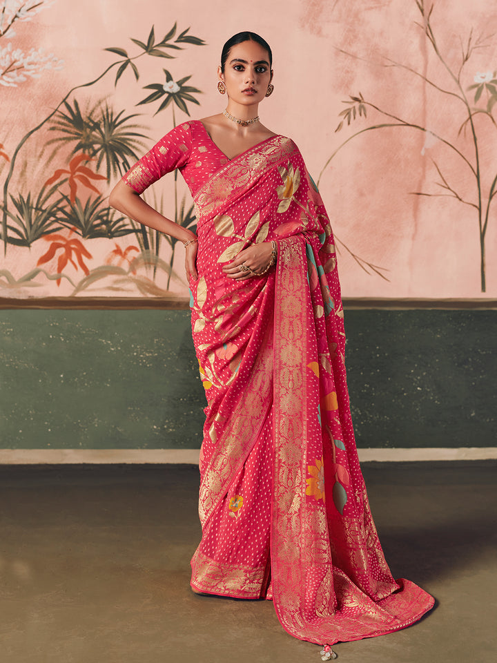 Woman wearing a pink saree with a floral pattern against a decorative wall.