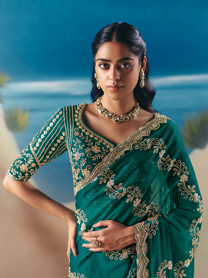 Woman in a green saree with gold embroidery against a blurred natural background