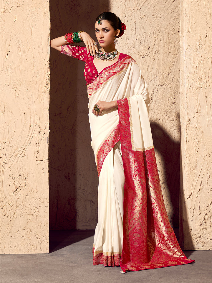 Woman wearing a white and red saree against a beige wall.