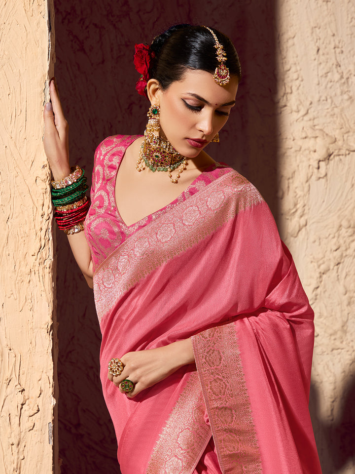 Woman in a pink saree with jewelry against a textured wall