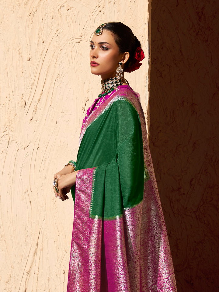 Woman in a green and pink traditional outfit against a textured wall.