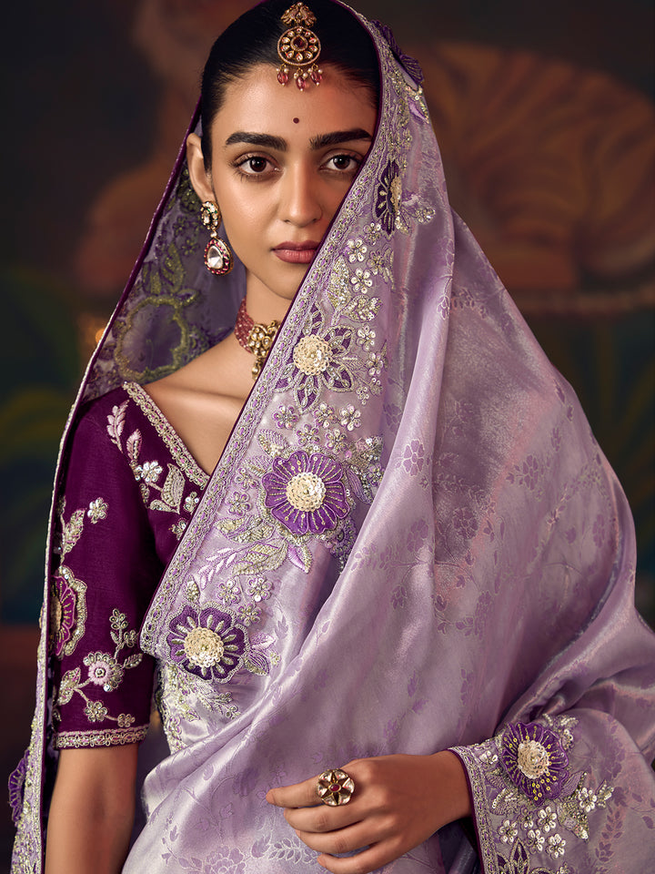 Woman wearing a traditional embroidered outfit with a purple and white color scheme.