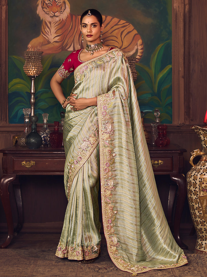 Woman in a green saree with a tiger painting in the background