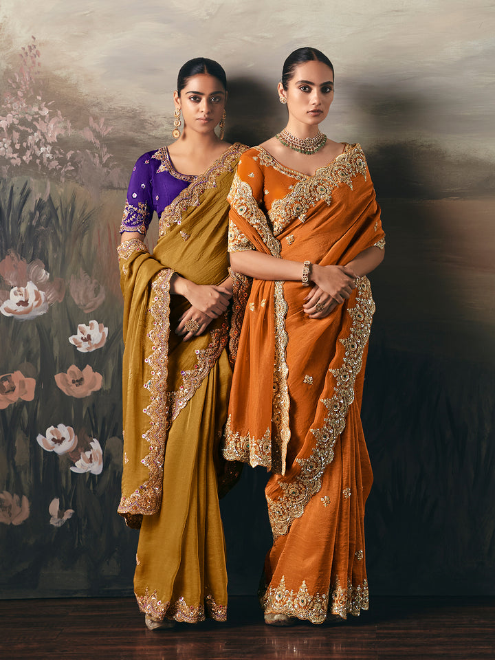 Two women in traditional sarees standing against a floral backdrop