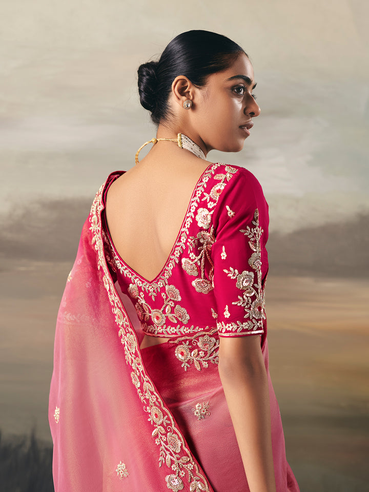 Woman wearing a pink saree with gold embroidery against a neutral background