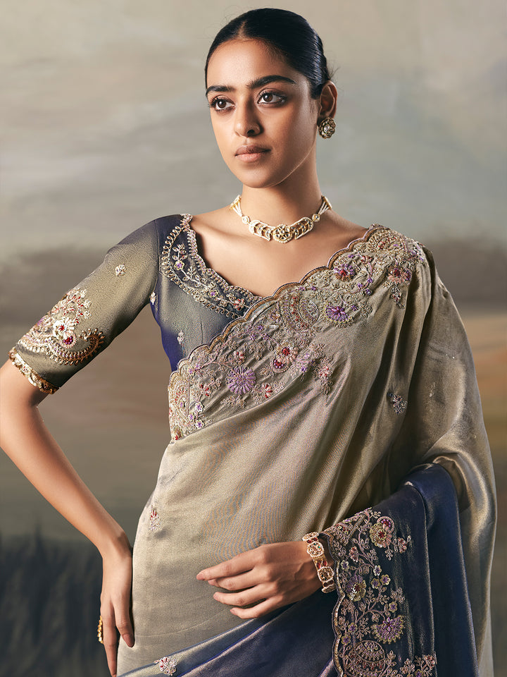 Woman wearing an embroidered saree with a neutral background