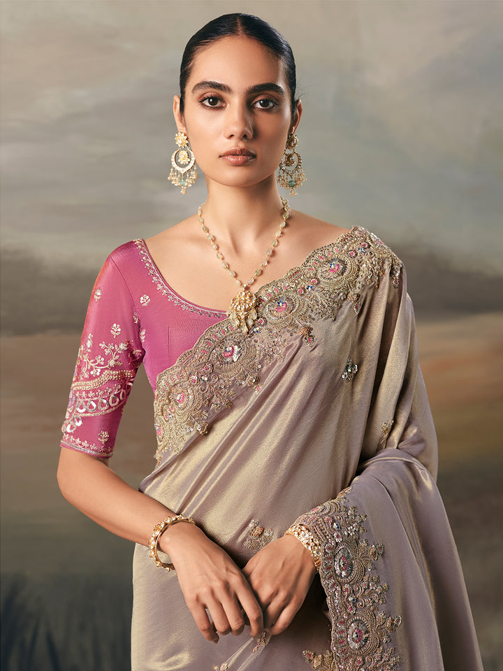 Woman wearing a traditional saree with intricate designs and jewelry against a neutral background