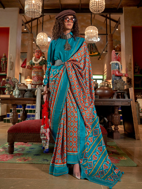 Woman in a blue patterned saree standing in a decorated room with hanging lights and decorative items.