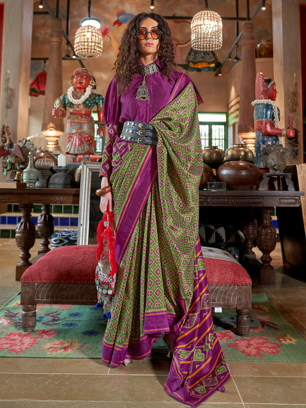 Woman in a traditional saree standing in a decorated room with colorful decor.