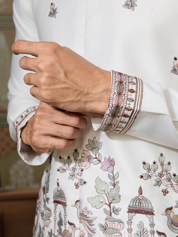 Close-up of a hand wearing a white embroidered sleeve with intricate patterns.