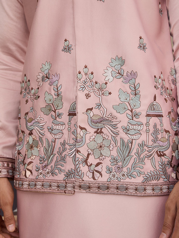 Pink embroidered garment with intricate designs on a matching pink background