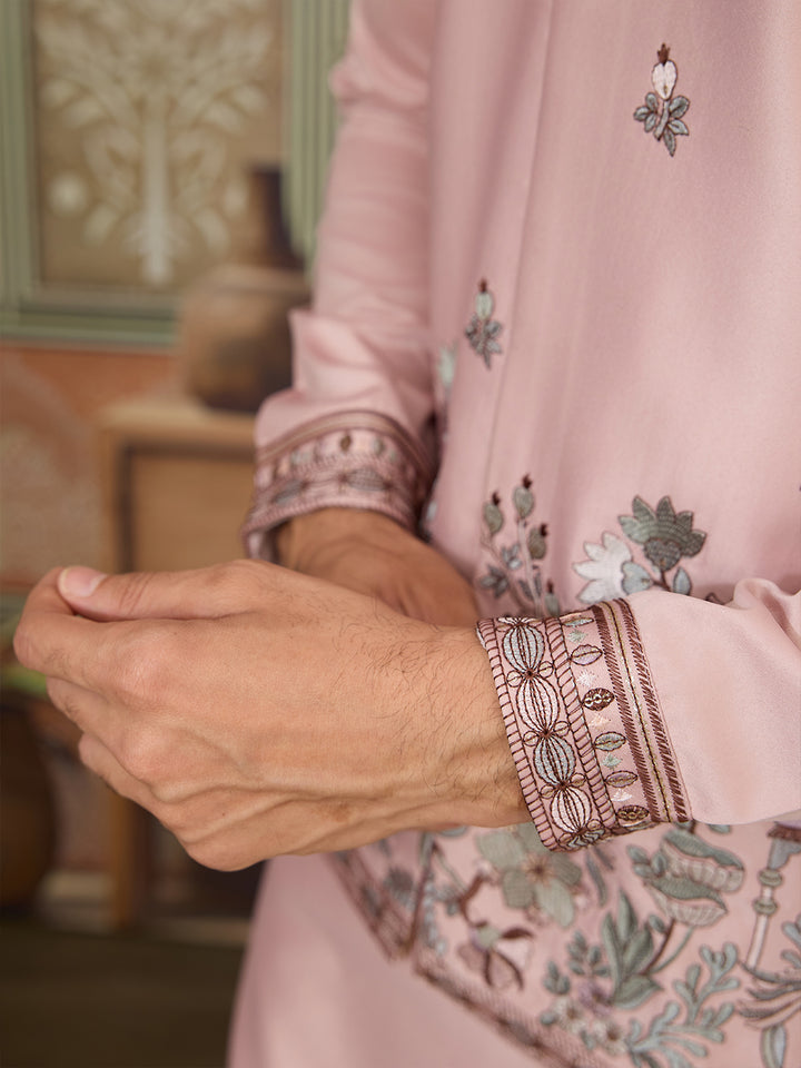 Close-up of a person wearing a pink embroidered outfit with intricate patterns.