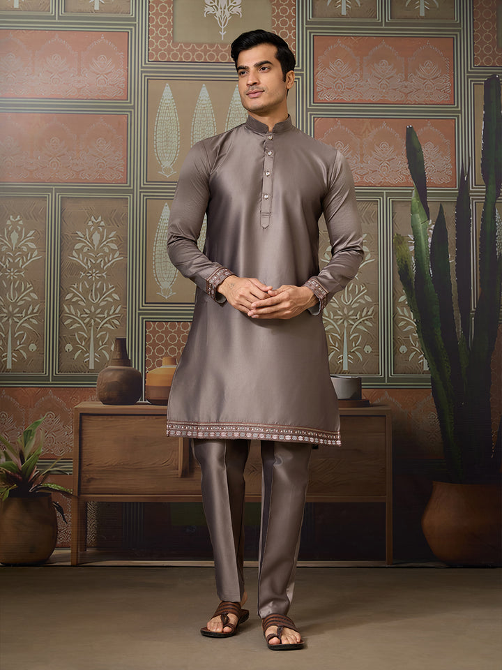 Man wearing a gray kurta with intricate patterns in a decorated room.