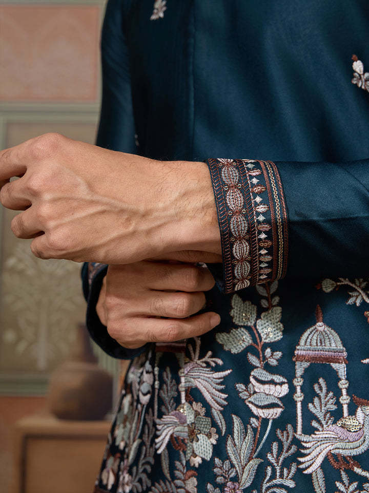 Close-up of a person wearing a dark blue embroidered garment with intricate patterns.