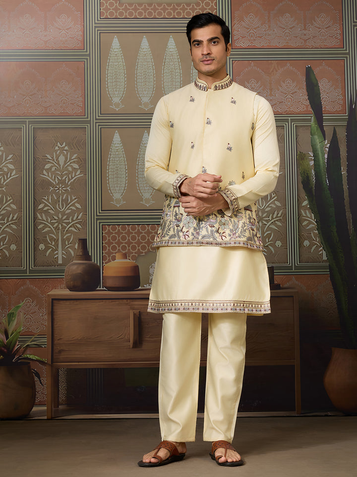 Man wearing a cream traditional outfit with intricate patterns in a decorated room.