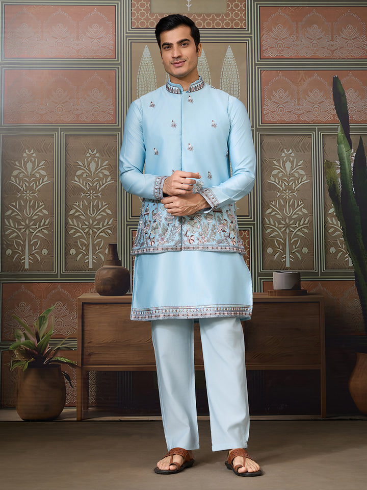 Man wearing a light blue traditional outfit in a decorated room.