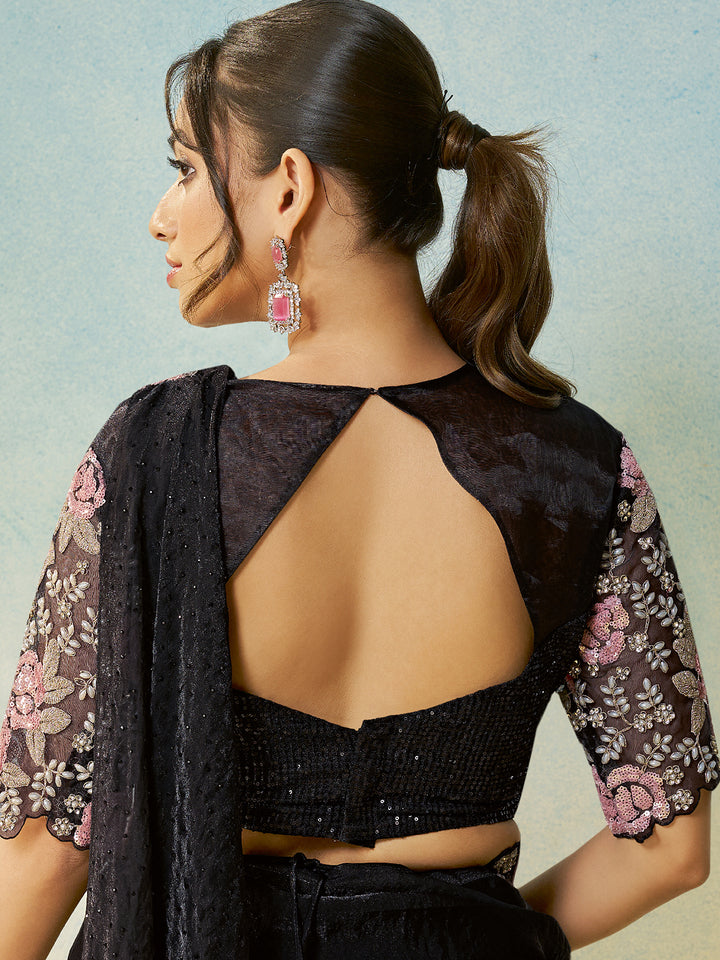 Woman wearing a black blouse with floral sleeves against a light blue background