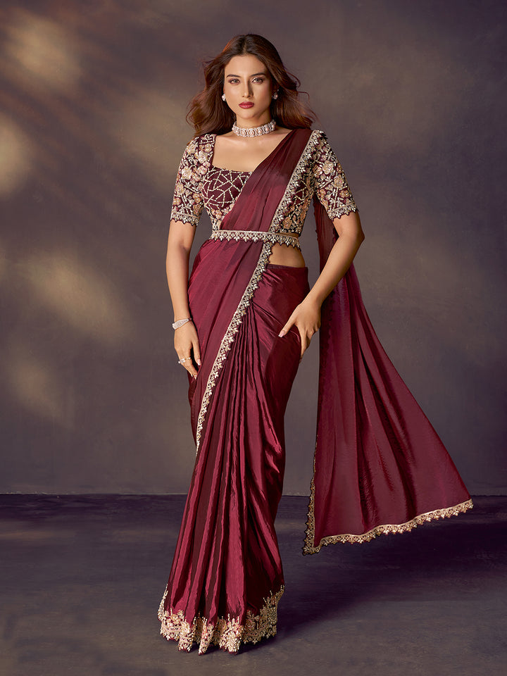Woman wearing a maroon saree with gold embroidery against a dark background