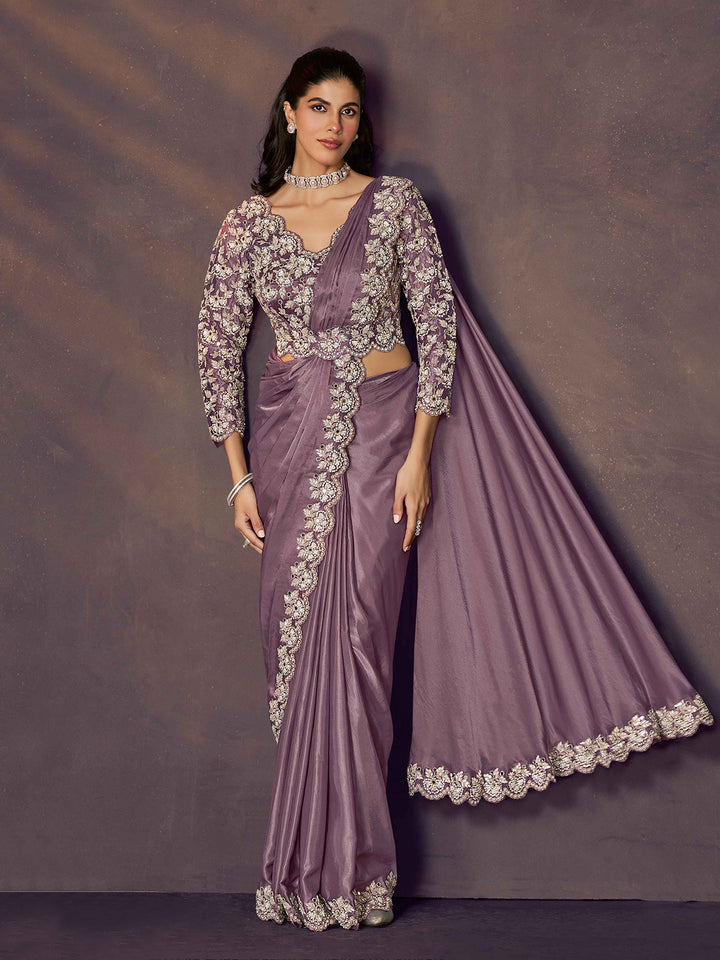 Woman wearing a purple saree with silver embroidery against a dark background