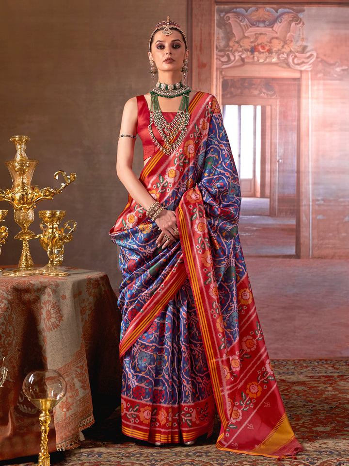 Woman in a colorful saree with intricate patterns in a decorated room.