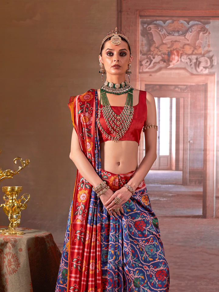 Woman in traditional red and blue saree with jewelry in a decorated room