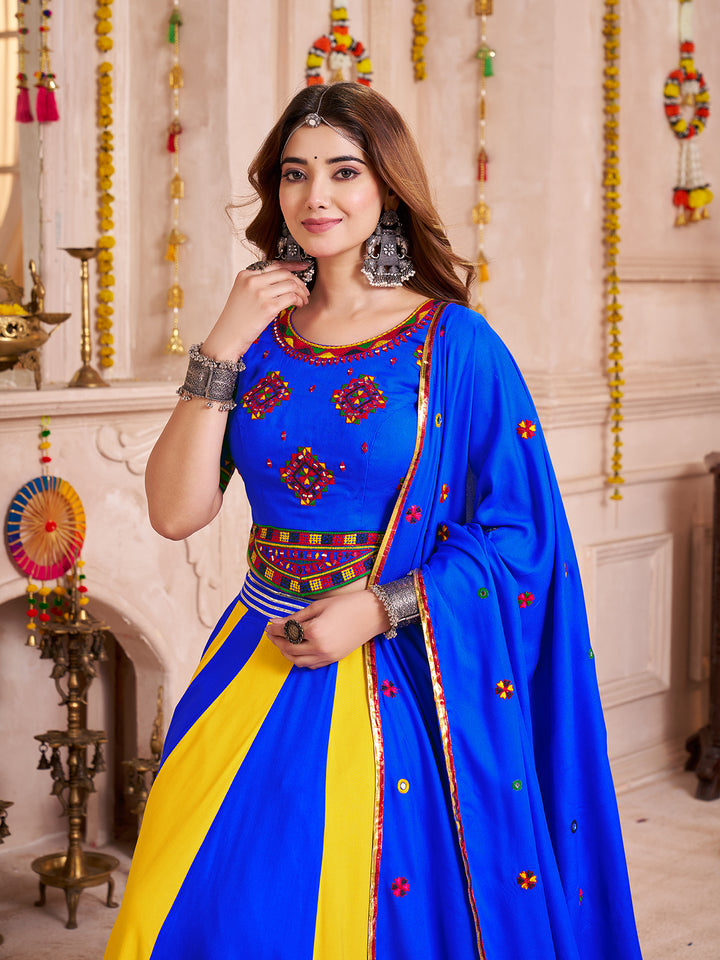 Woman wearing a traditional blue and yellow outfit with decorative elements indoors.