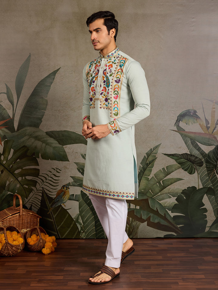 Man wearing a traditional embroidered kurta with a decorative background