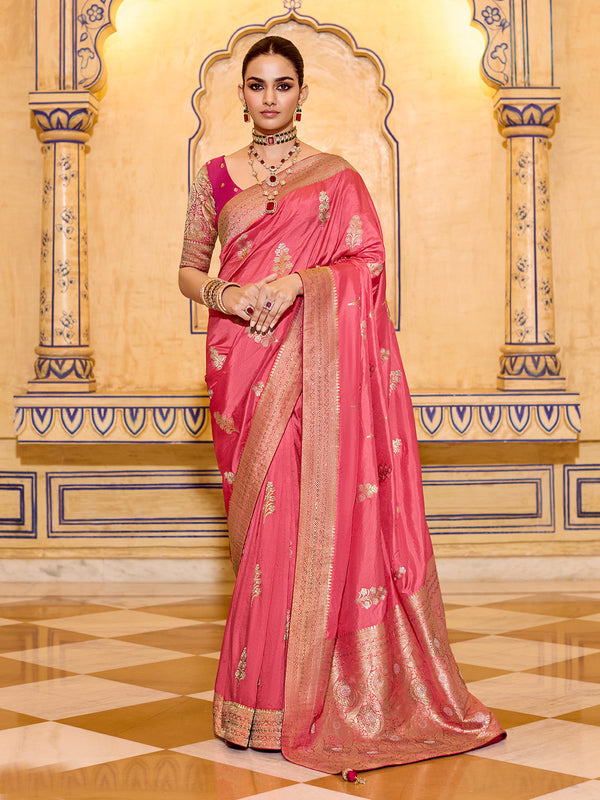 Woman in a pink saree with gold details standing in an ornate room.