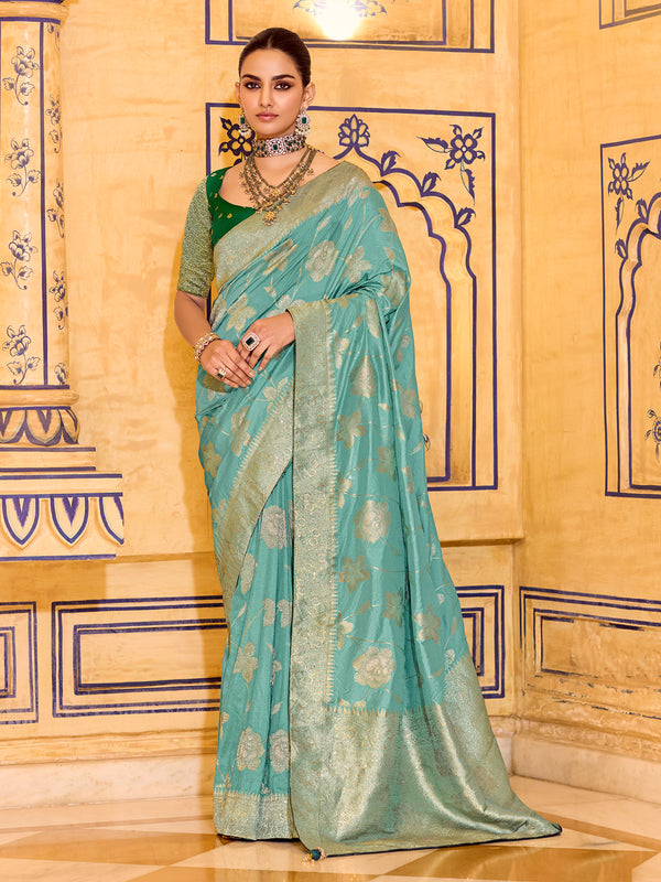 Woman wearing a light blue saree with a green blouse in an ornate room.