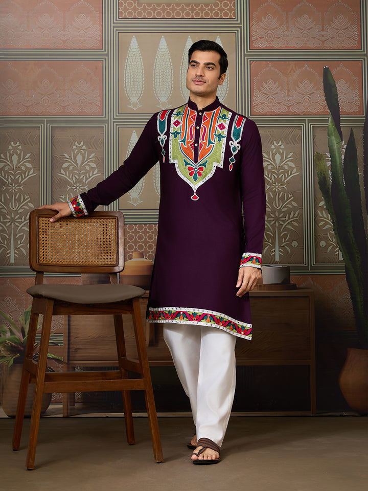 Man wearing a traditional embroidered kurta with a colorful neckline in a decorative room.