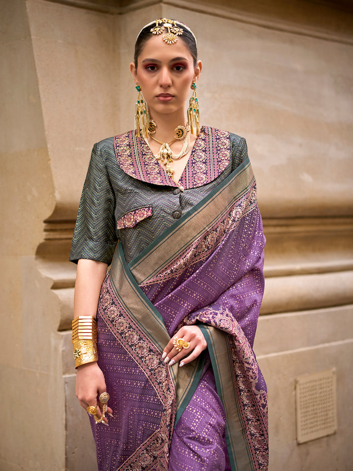 Woman wearing a traditional saree with intricate patterns and jewelry against a neutral background
