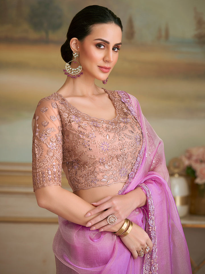 Woman wearing a pink saree with a matching blouse in an elegant setting.