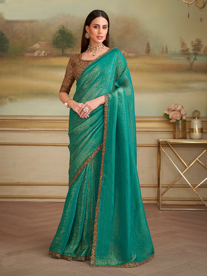Woman wearing a teal saree with gold border in an elegant indoor setting