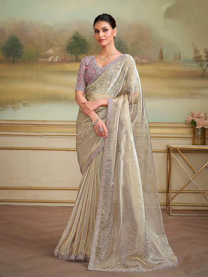 Woman in a traditional saree standing in a room with a scenic wall painting.