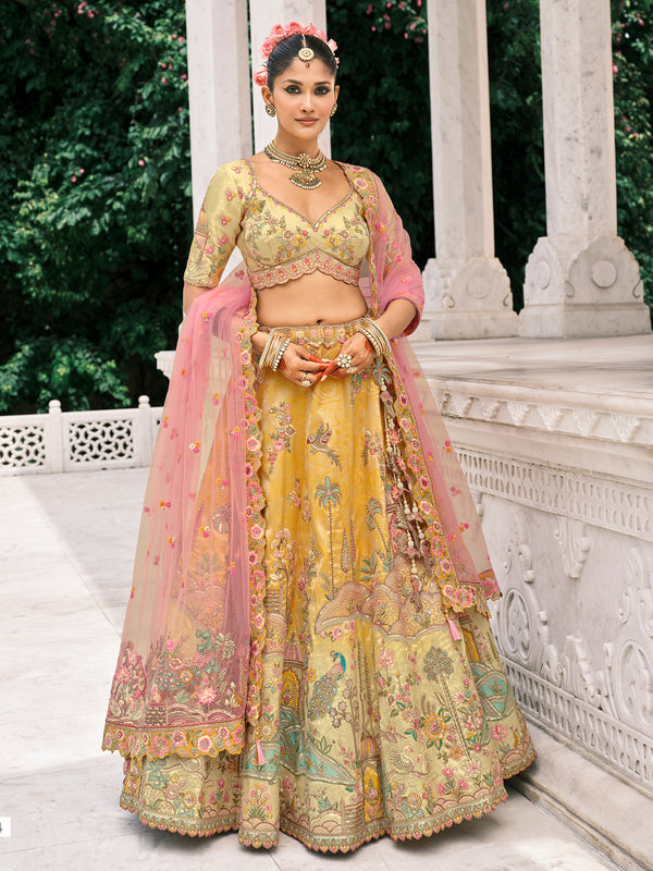 Woman in traditional yellow and pink embroidered outfit standing in front of a white architectural structure.