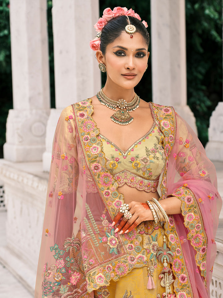 Woman in traditional Indian attire with floral jewelry and makeup, standing against a white architectural background.