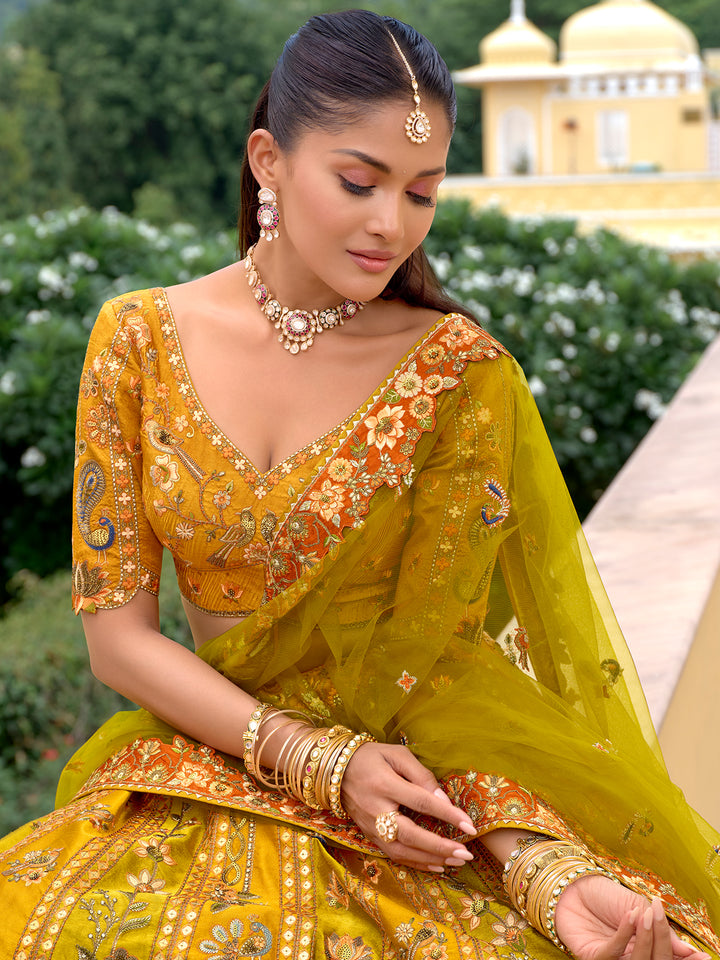 Woman in a traditional yellow and green embroidered outfit with jewelry, outdoors.