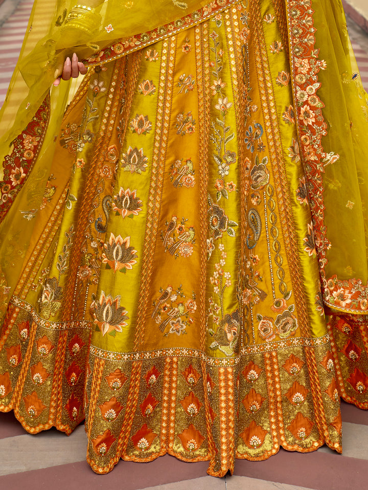 Yellow traditional outfit with intricate orange and red embroidery on a patterned floor.
