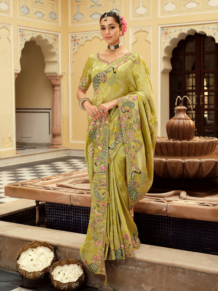 Woman in a traditional green saree with floral patterns in an ornate indoor setting.