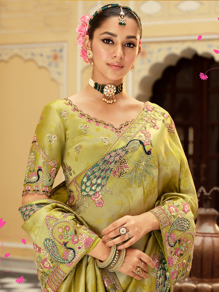 Woman wearing a traditional embroidered saree with peacock designs in a decorative setting.