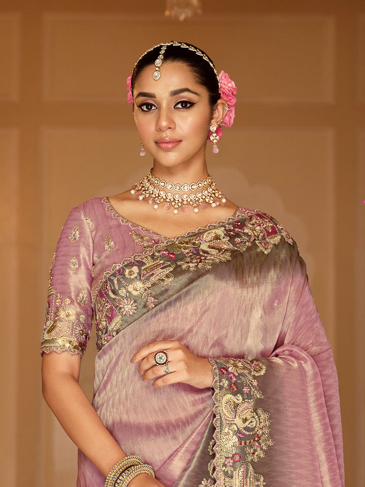 Woman wearing a traditional saree with intricate designs and jewelry against a neutral background