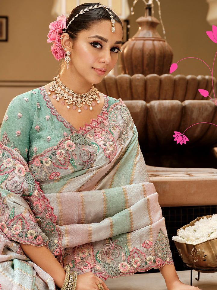 Woman in traditional embroidered saree with jewelry, sitting indoors.