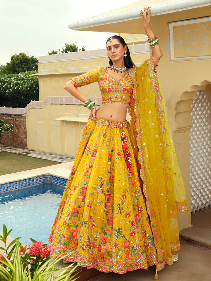 Woman in a yellow floral lehenga standing by a pool with decorative architecture in the background
